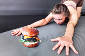 Willpower. Fitness woman trains willpower. Athletic girl tempts herself with a delicious burger at...