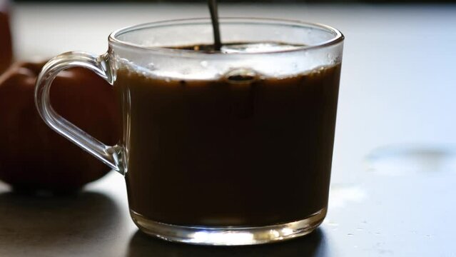 Stir sugar and coffee with a spoon in a transparent glass