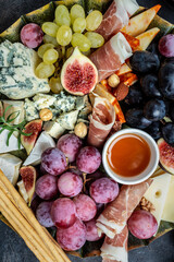 Appetizers table with italian antipasti snacks and wine in glasses. cheese, ham, nuts, fruit, bread sticks. Delicious balanced food concept