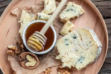 Tasty blue cheese on a wooden background and burlap. Dorblu cheese pieces, Food recipe background. Close up
