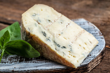 Danish blue cheese. Tasty blue cheese on a wooden background and burlap. Dorblu cheese pieces. Food recipe background. Close up