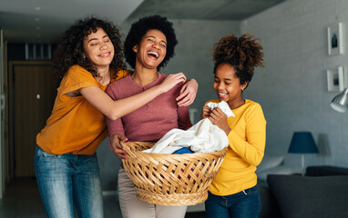 Happy multiethnic teenage children are smiling while do household with mother at home.
