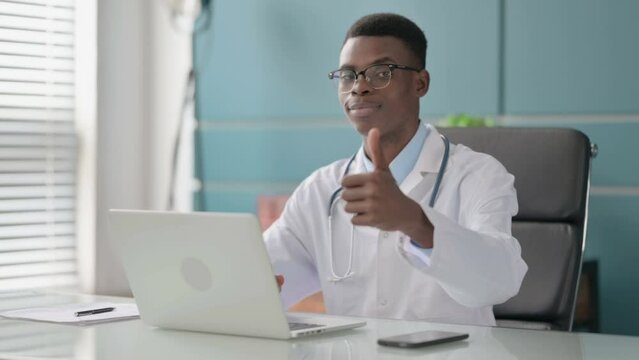 Young African Doctor Showing Thumbs Up Sign While using Laptop in Office 