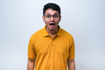 Obraz premium Amazed asian young man with open mouth and bulging eyes looking at camera