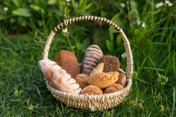Fototapeta na wymiar Assorti of brown and white homemade bread in wicker basket standing on the grass