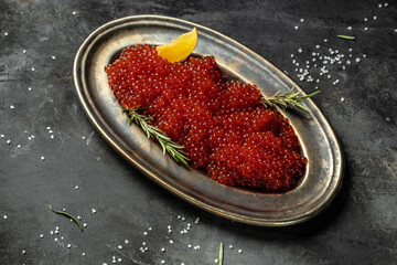 Delicious red caviar in black bowl on a concrete background. banner, menu, recipe. selective focus, place for text