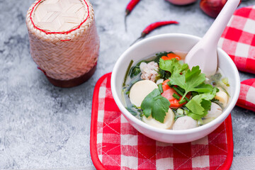 Boiled tofu and minced pork served in white cups with red checkered saucers placed on a white table.