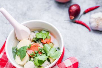 Boiled tofu and minced pork served in white cups with red checkered saucers placed on a white table.