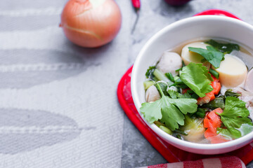 Boiled tofu and minced pork served in white cups with red checkered saucers placed on a white table.
