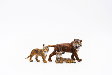 Toy animal figures tiger and tiger cubs on white.	