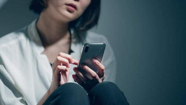 精神障害を患っている若い女性がスマートフォンを使っている