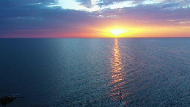 Flight over a sunny path to a lighthouse on an island and a beautiful sunrise. Ahtopol, Bulgaria. 4K