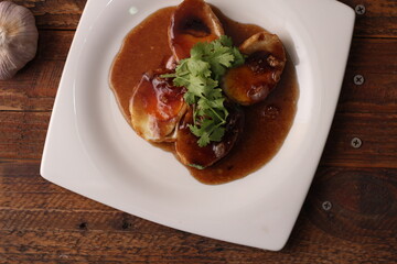 Egg with Tamarind Sauce in a white plate served on a wooden table with coriander sprinkles, is a popular local dish that Thai people eat.