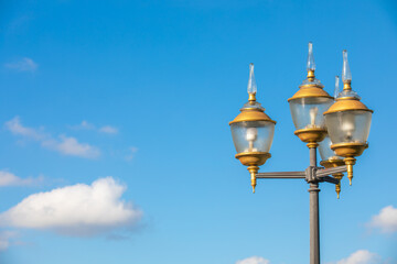 Electric lighting lamp post or pole against blue sky and white clouds.