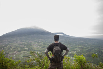 Man hiker with a backpack on top of the mountain back, the concept of motivation and goal achievement
