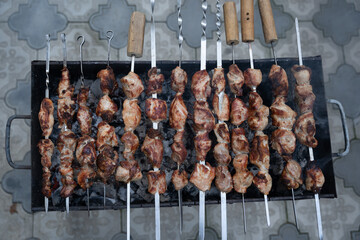 Georgian national dish meat on a spit, grilled on a large metal grill with hot charcoal, the meat is golden brown.