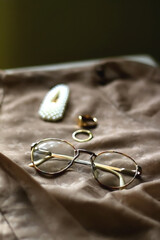 Brown vintage blouse, retro eyeglasses, pearl hair clip and gold rings. Selective focus.