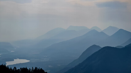 Scenic view on the alpine mountain chains of the Karawanks in Carinthia, Austria. Peaks are shrouded in morning fog. Mystical vibes. Clear and sunny day.  Serenity. View from Ferlacher Spitze, Alps