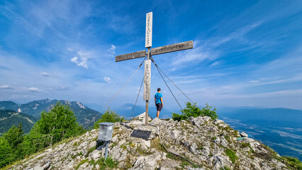 Fototapeta na wymiar Man admiring the scenic view from summit cross of Ferlacher Spitze on Mittagskogel in the Karawanks, Carinthia, Austria. Borders between Austria, Slovenia, Italy. Rosental valley