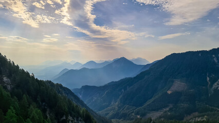 Scenic view on the alpine mountain chains and woodland of the Karawanks in Carinthia, Austria. Peaks are shrouded in morning fog. Mystical vibes. Ssunny day. Serenity. View from Ferlacher Spitze, Alps