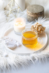 Cup of herbal tea and burning candle on round white decorative tray