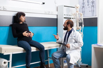 Pregnant woman meeting with doctor at checkup appointment. Physician doing consultation with...