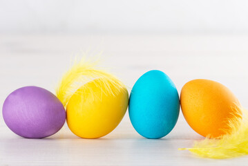 Multicolored Easter eggs with feathers on a wooden background.