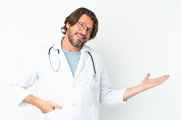 Senior dutch man isolated on white background wearing a doctor gown and presenting something
