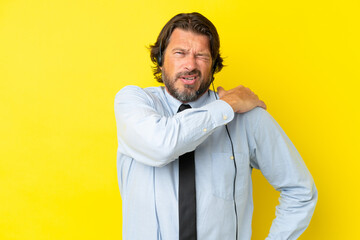 Telemarketer dutch man working with a headset isolated on yellow background suffering from pain in shoulder for having made an effort