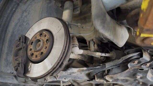 view of the front suspension of the car from below. brake disc, caliper, tie rod, lever, drive, anthers, silent blocks, shock absorber, subframe