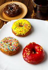 Group of glazed donuts. Fast sweet food concept in white and brown plates on wooden table