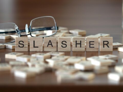 Slasher Word Or Concept Represented By Wooden Letter Tiles On A Wooden Table With Glasses And A Book