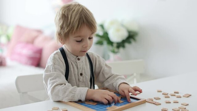 Preschool child, cute blond boy, playing with wooden numbers at home on the table