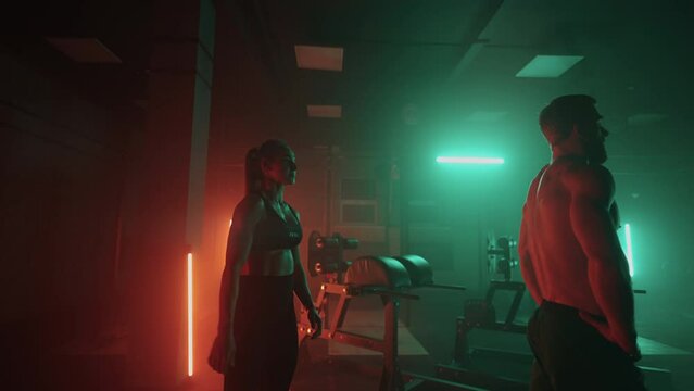 male and female jocks are exercising in gym in night, playful pair of sporty people