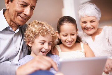Kids with grandparents. A shot of two kids and their grandparents using a digital tablet while...