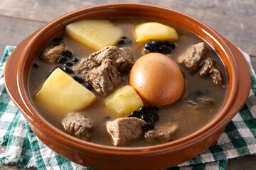 Traditional Jewish cholent in bowl on wooden table	