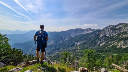Fototapeta na wymiar Man admiring the scenic view near Mittagskogel on the mountain peaks in the Karawanks, Carinthia, Austria. Borders between Austria, Slovenia, Italy. Julian Alps, Triglav National Park. Mystical hills