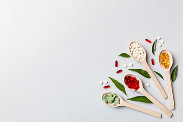 Top view Variety of vitamin and mineral pills in wooden spoon on Colored background. Top view of...