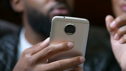 Candid couple sitting together in bedroom looking at smartphone device