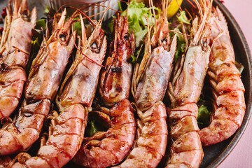 Grilled king prawns with sauce on platter close up