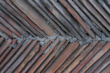 brown clay tiles walled together with concrete form a triangular shape and structure.