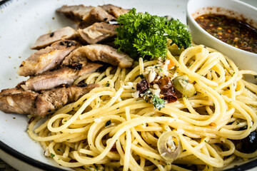 Close up grilled pork neck spaghetti with spicy sauce in white dish. Image selective focusing. 