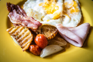 Close up image of breakfast set in yellow dish. Image lighting set chiaroscuro style. 