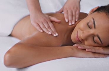 The perfect stress reliever. Shot of a beautiful young woman enjoying a back massage at a spa.