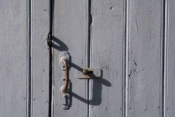 old wooden doors with peeling off paint and old rusty door handles.