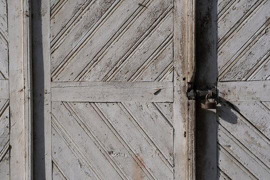 old wooden doors with peeling off paint and old rusty door handles.