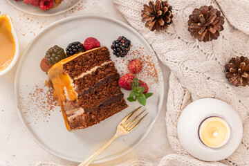 Delicious semi-naked chocolate cake with caramel topping and decorated with blackberries and raspberries. Light background