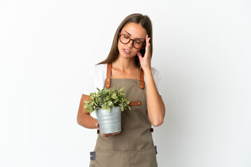 Gardener girl holding a plant over isolated white background with headache