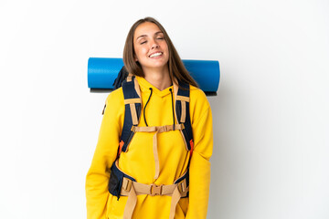 Young mountaineer woman with a big backpack over isolated white background laughing