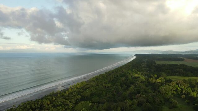 Aerial shot of a beautiful long beach in costa rica. Sunny day close to the pacific ocean and the tropical forest